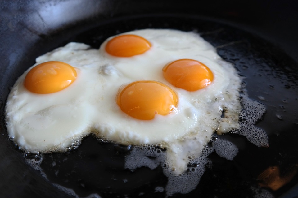 Four sunny-side-up eggs frying in a pan